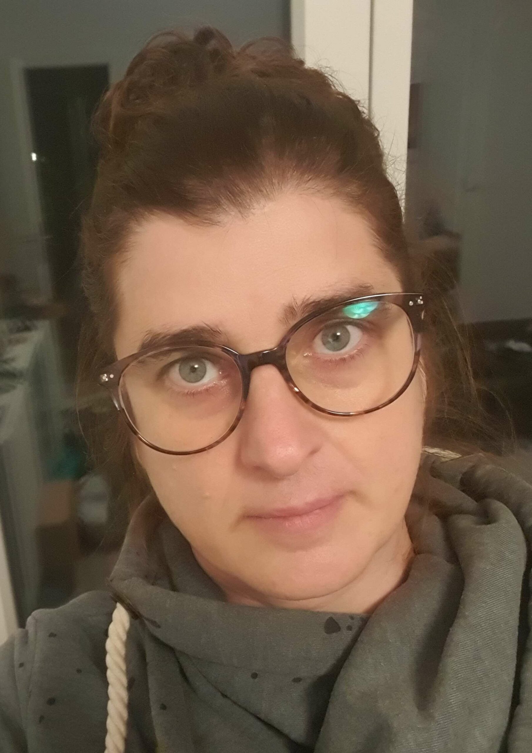 Foto einer Frau mit großer Brille, hochgesteckten braunen Haaren und Hoodie