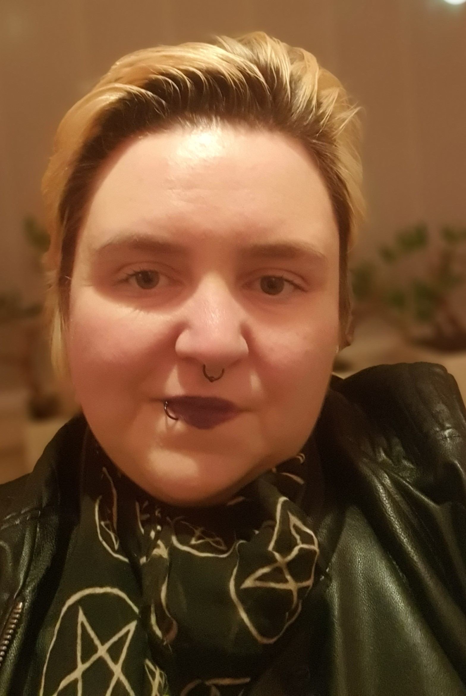 Foto einer Person mit nach hinten gegelten blonden Haaren, Piercings, einer Lederjacke und einem zerrissenen Halstuch